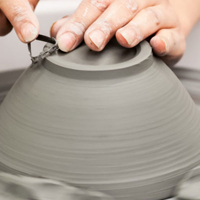 Hands fashioning a bowl on the potter's wheel