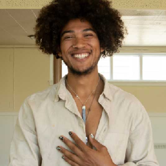 An Afro-Latino man smiling with his hand on his chest