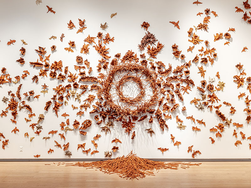 A wall-mounted installation of red clay birds