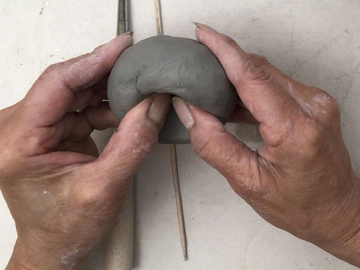 Pressing thumbs into a ball of clay