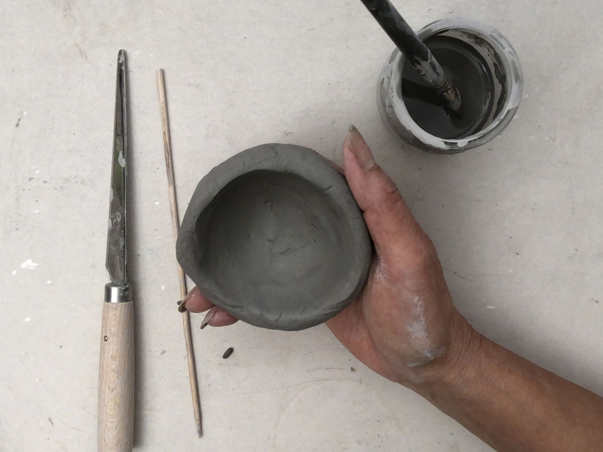 Hand holding a small clay pot