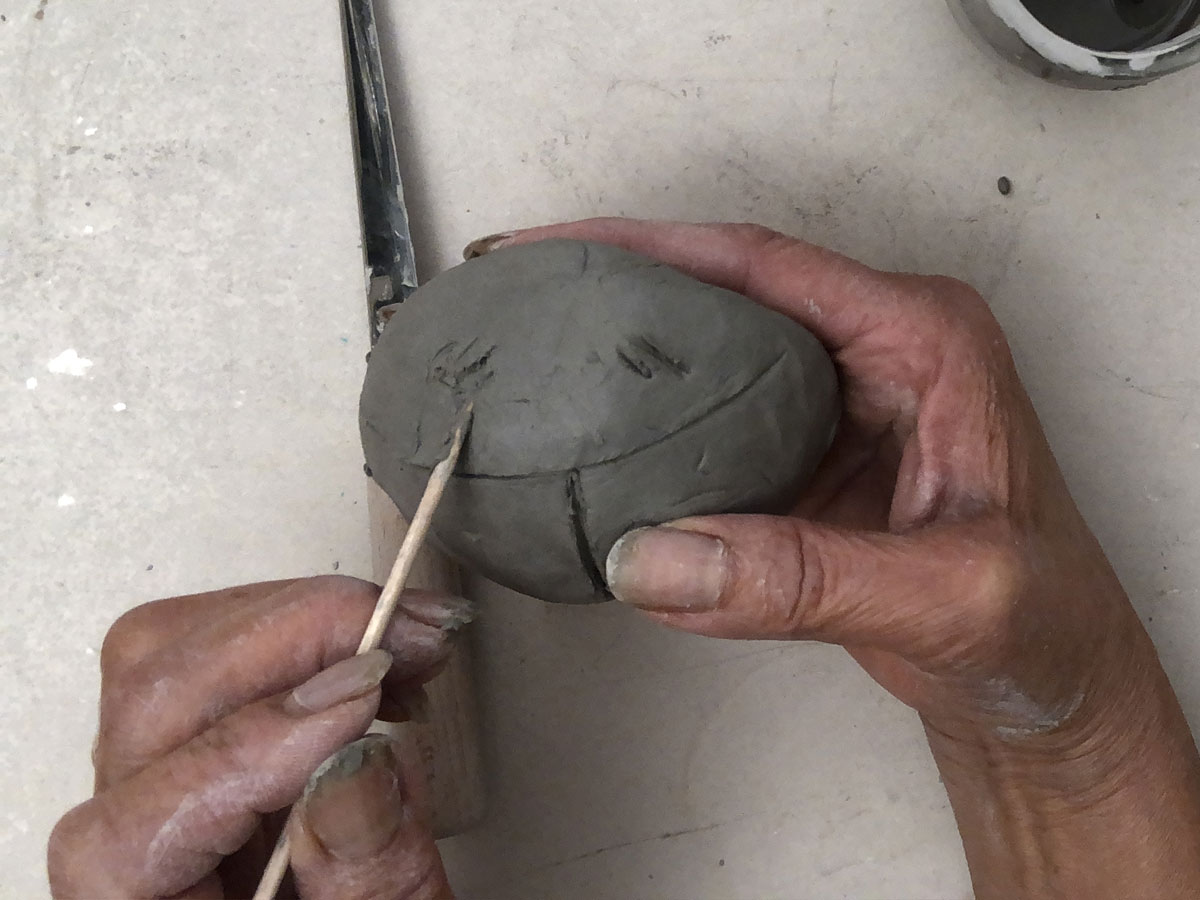 Scratching a clay ball with a wood skewer