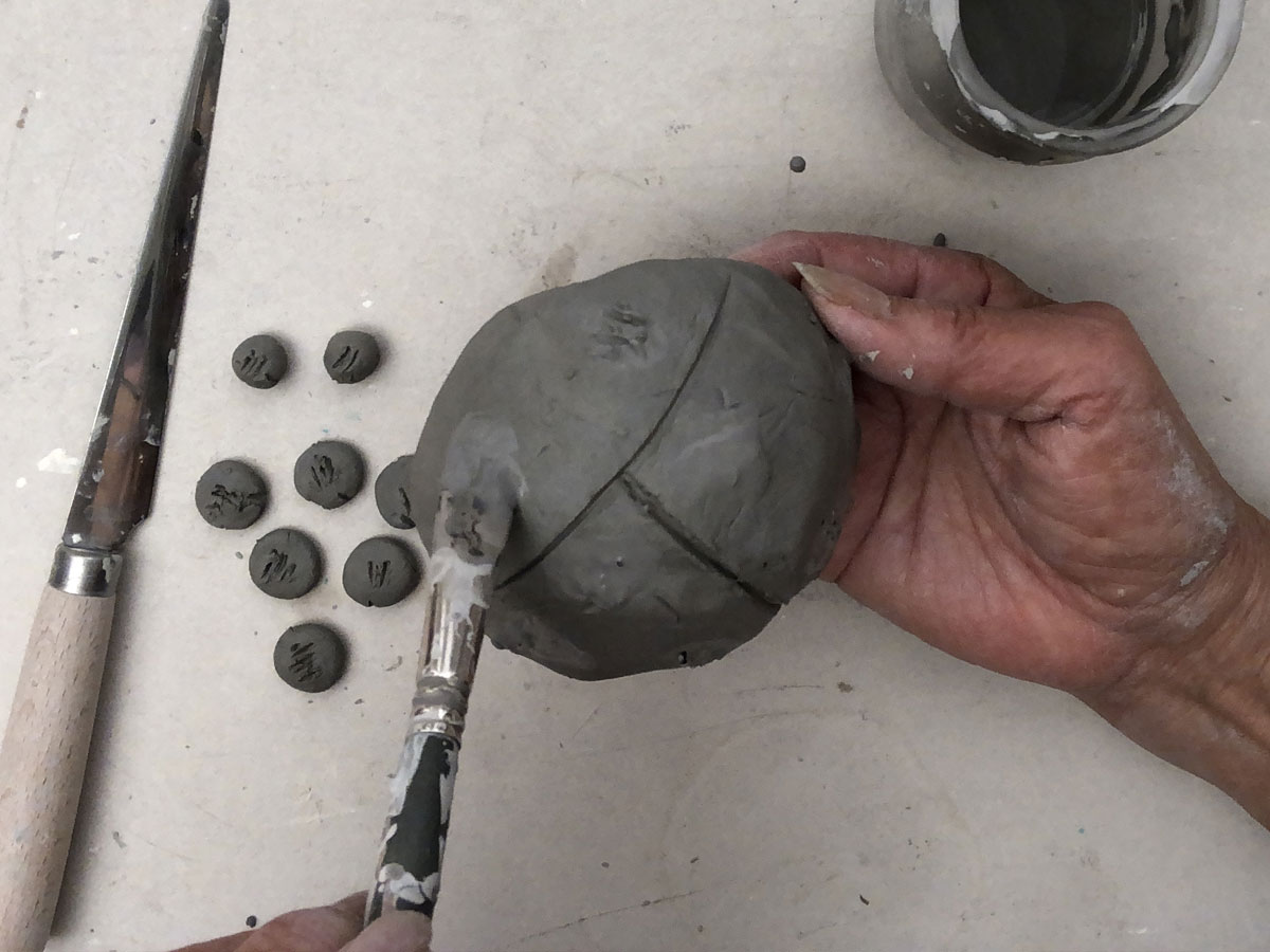 Sticking clay dots onto a clay ball