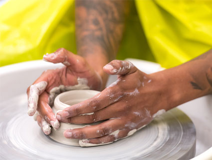 Hands of someone using the pottery wheel