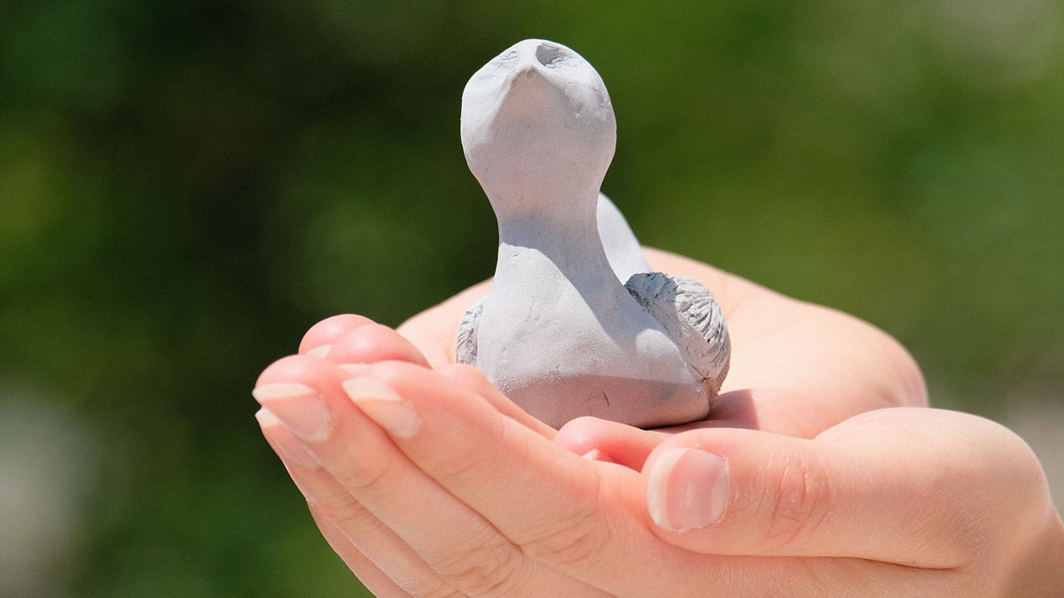Hands holding a clay bird