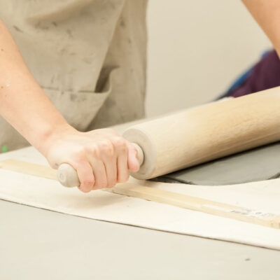 Person rolling out a slab of clay