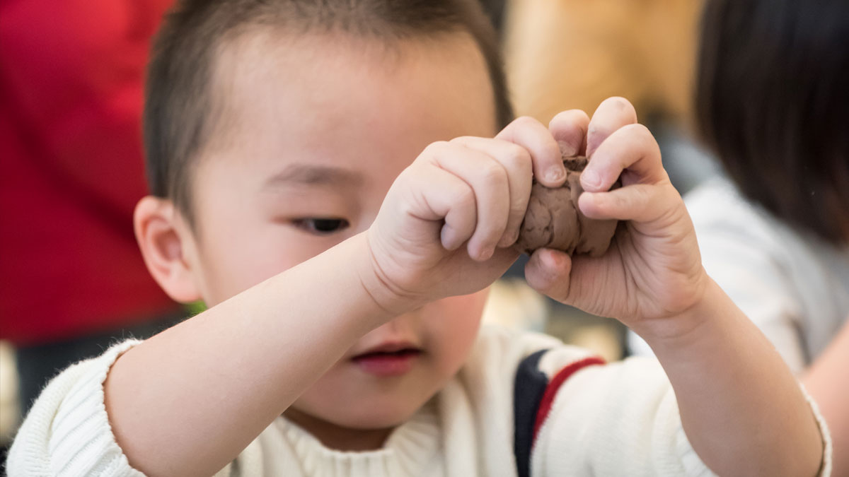 Child squeezing a ball of clay