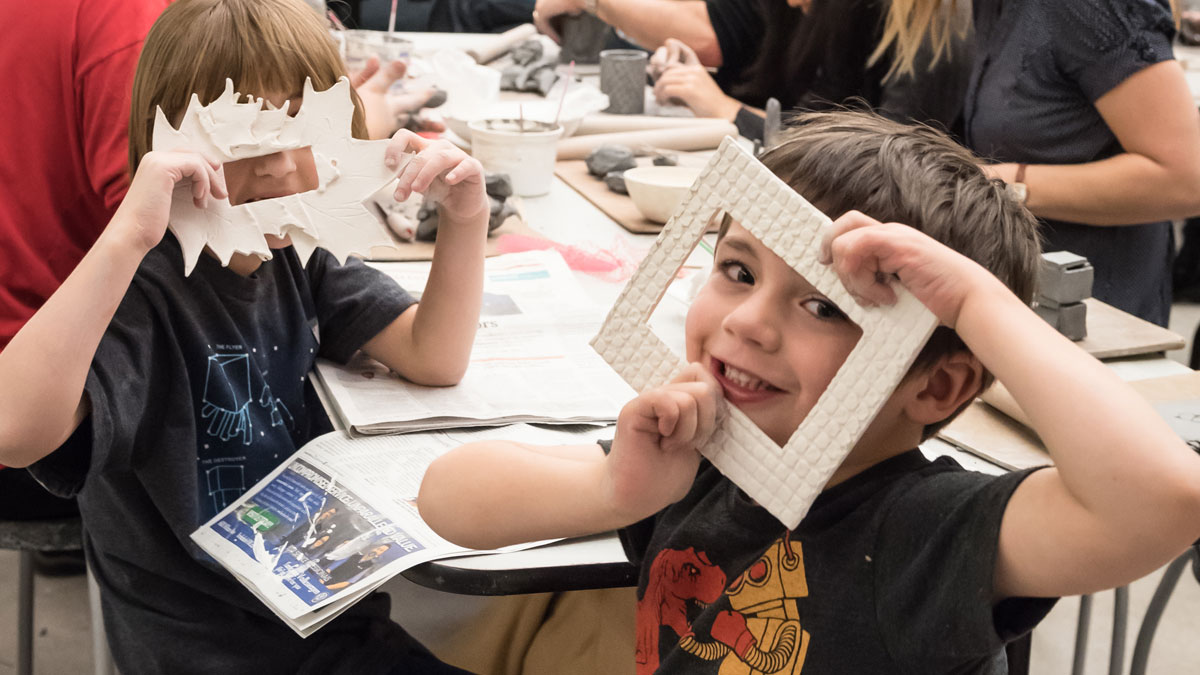 Kids holding ceramic frames up to their faces.