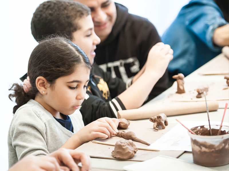 A father and his two children sculpting with clay