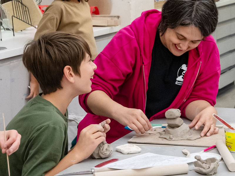 A mother and son laughing while making pottery in the studio