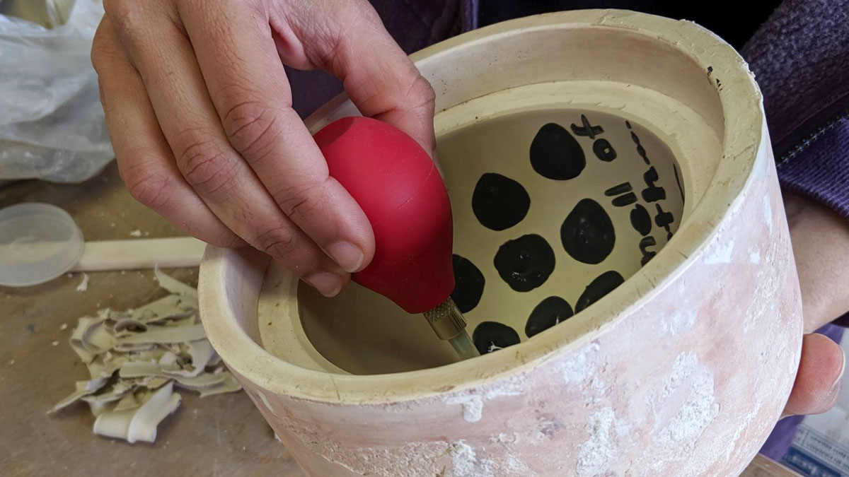 Hands of someone working on a ceramic pot