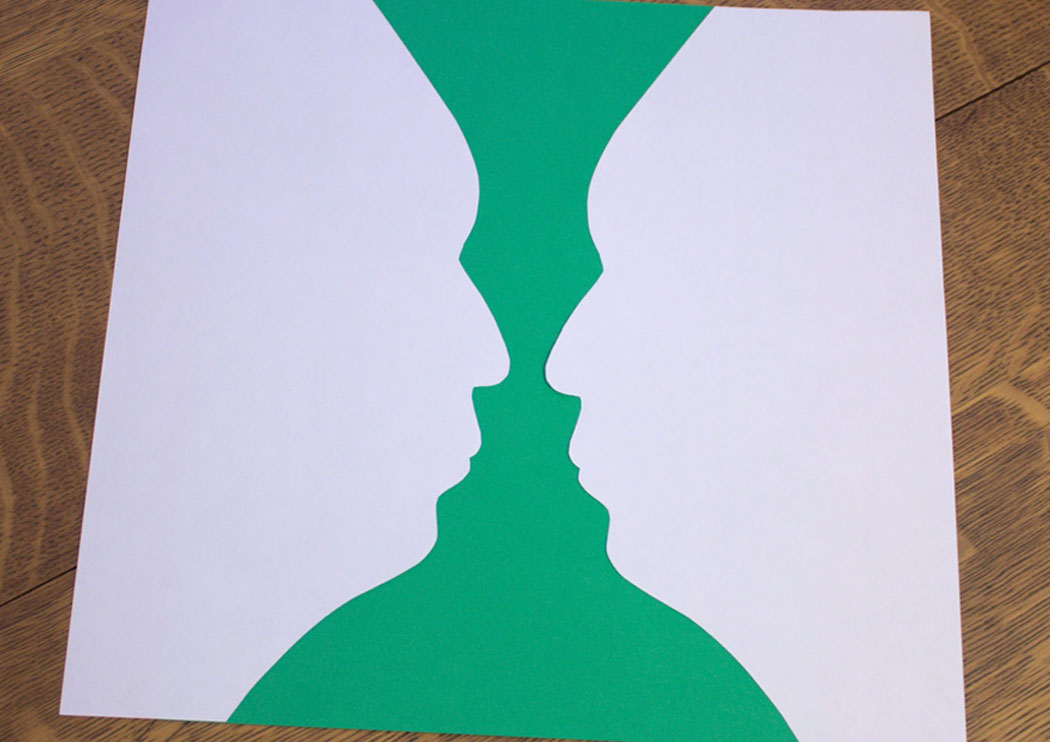 Two silhouettes of a face forming a vase in the negative space