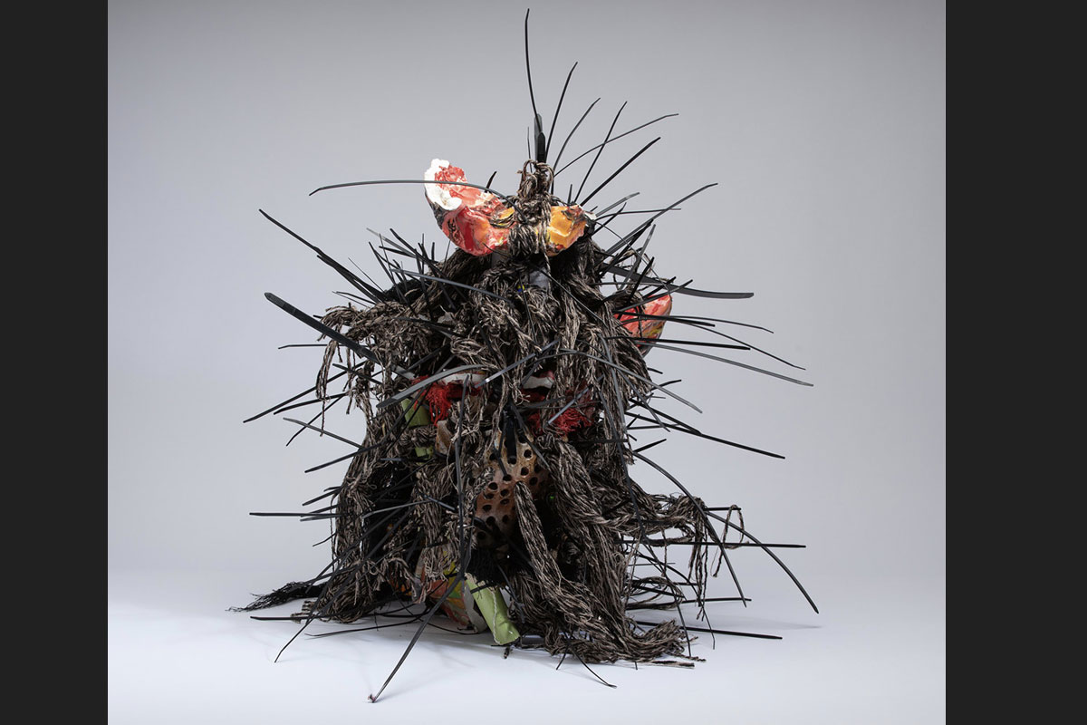 Abstract ceramic and mixed media sculpture with black spikes, braids, and colourful ceramic shards
