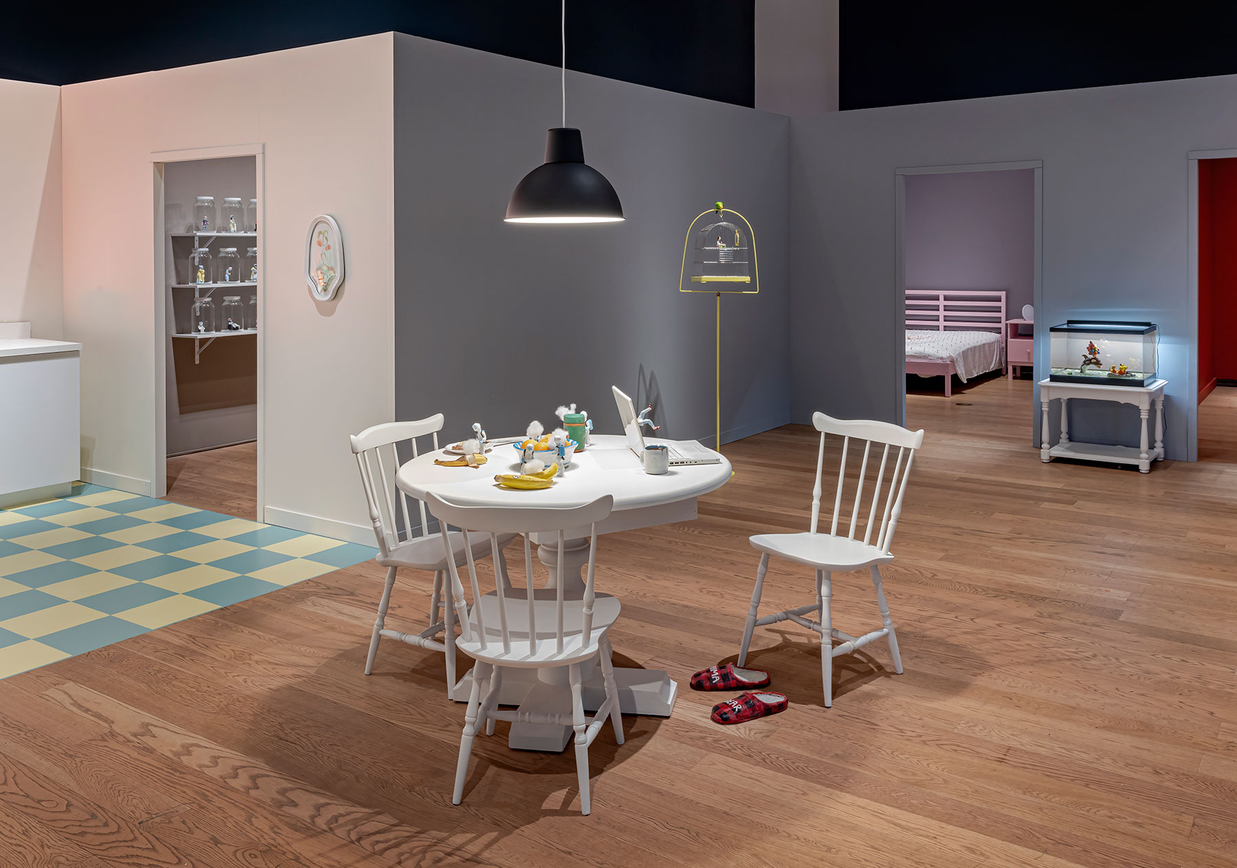 Installation view of Housewarming with a kitchen table and chairs visible inside a set of open doors