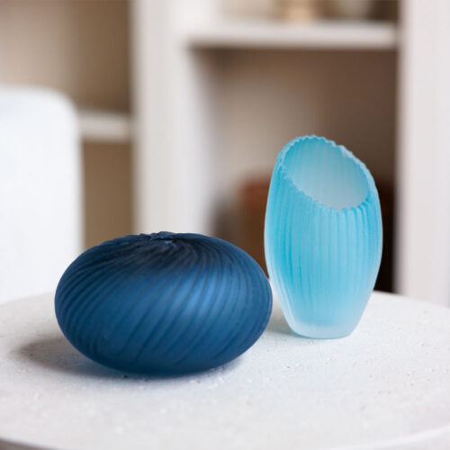A dark blue and a light blue glass vessel on a table
