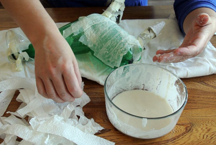 Hands dipping paper towel strips in paste
