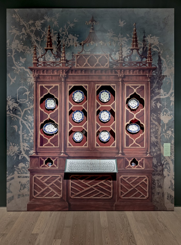 A painted wooden cabinet with real ceramic plates inserted in cutouts