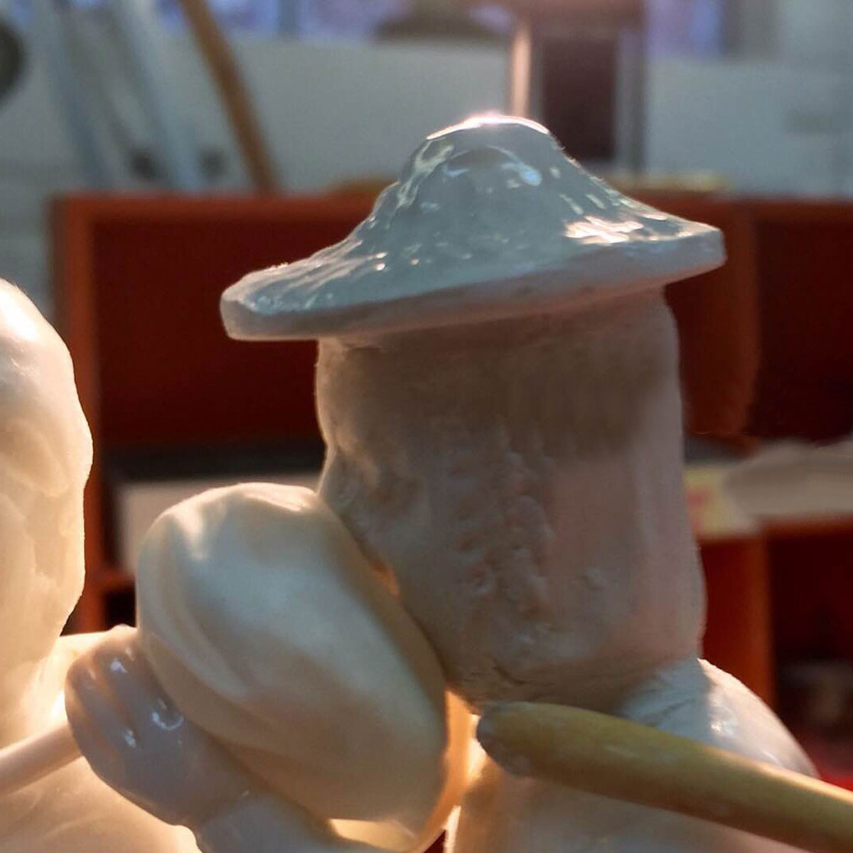 Head and hat of a white clay figure being attached together