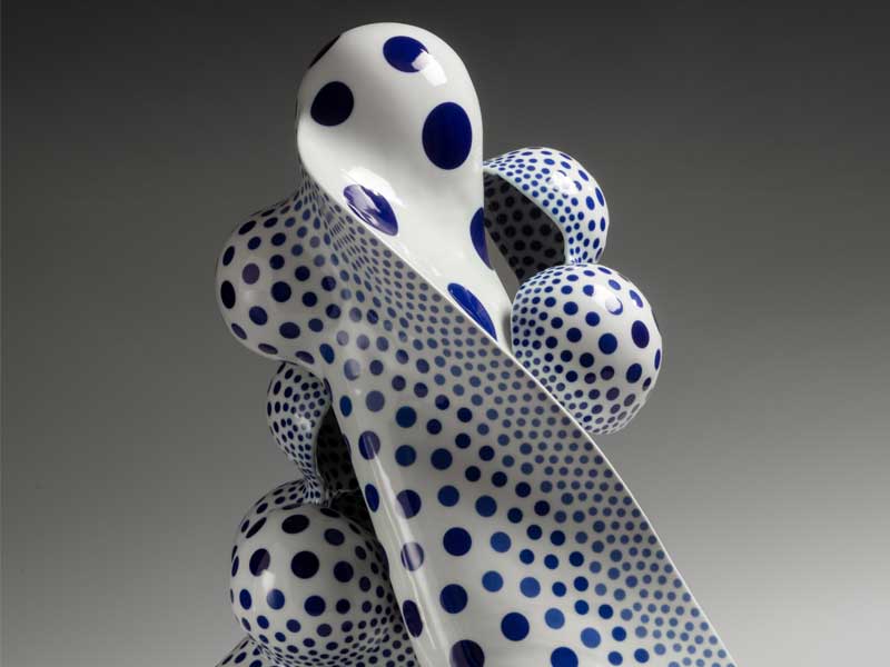 A white ceramic sculpture with blue polka dots
