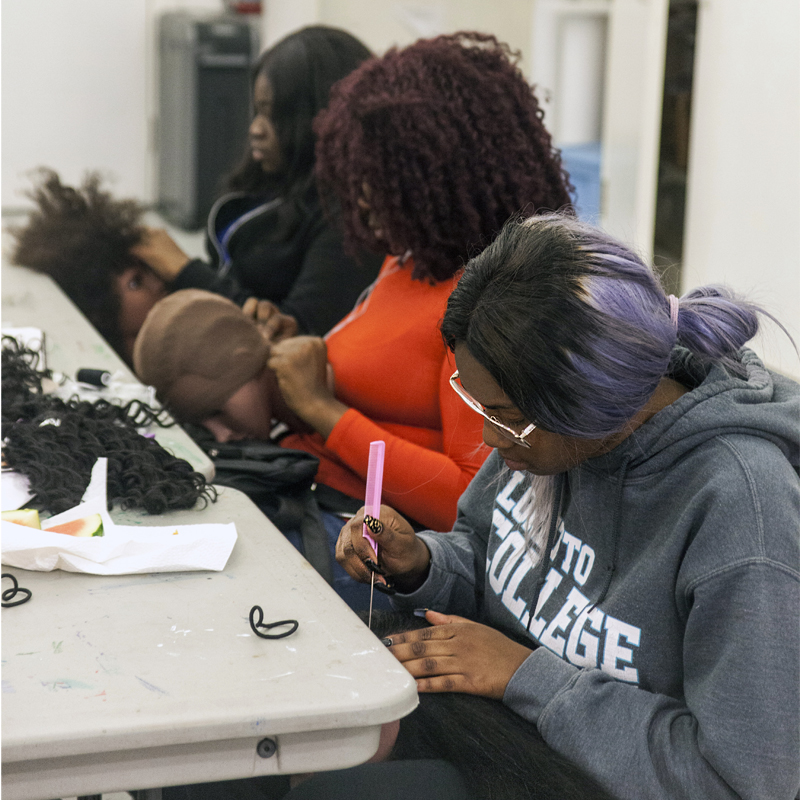 Three young women working on wigs