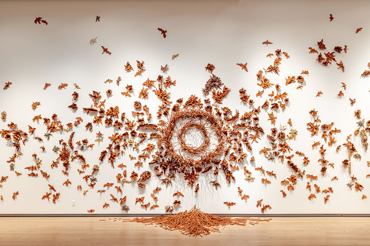 A wall-mounted installation of red clay birds