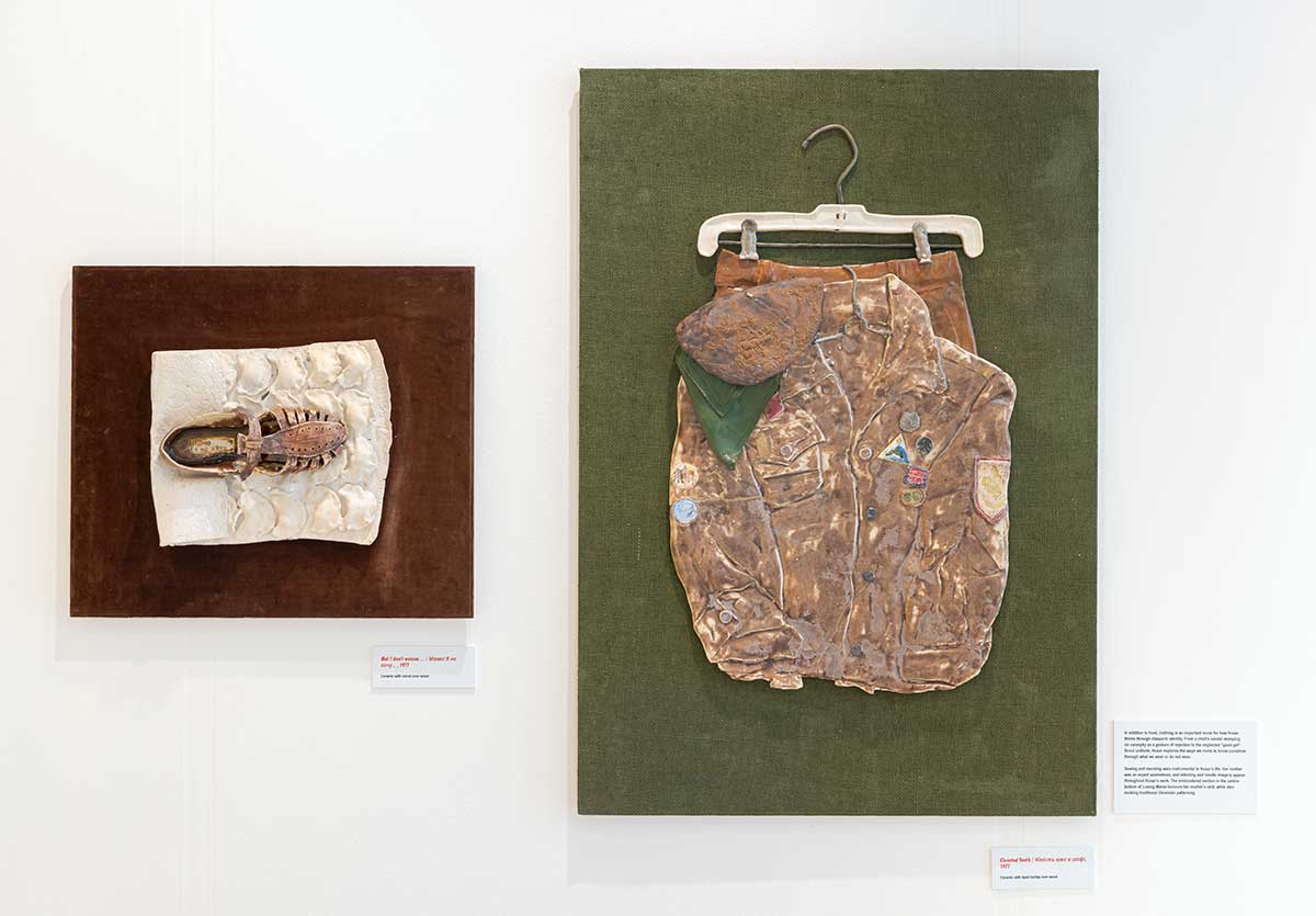 Two ceramic sculptures hung side-by-side, one of a shoe and one of a jacket