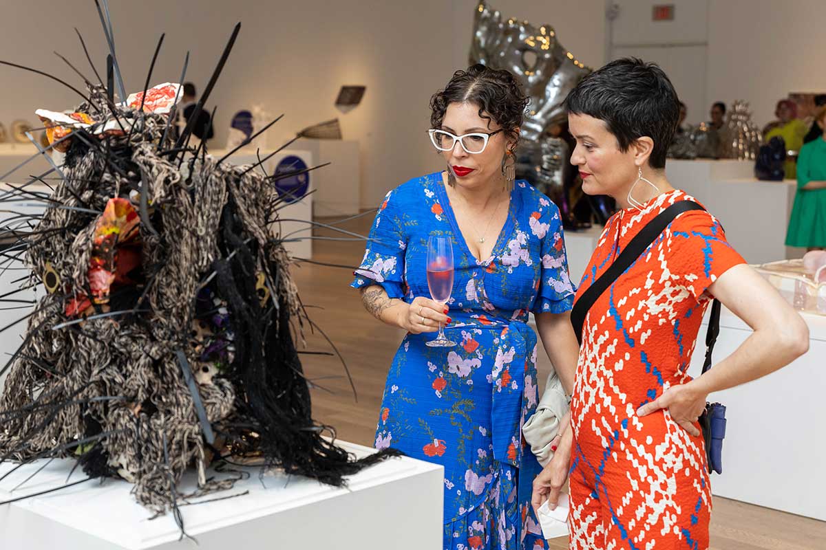 Two women looking at a sculpture with black spikey protrusions