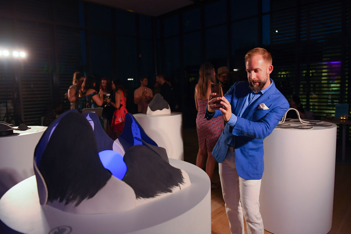 A party guest taking a photo of a ceramic artwork on a plinth