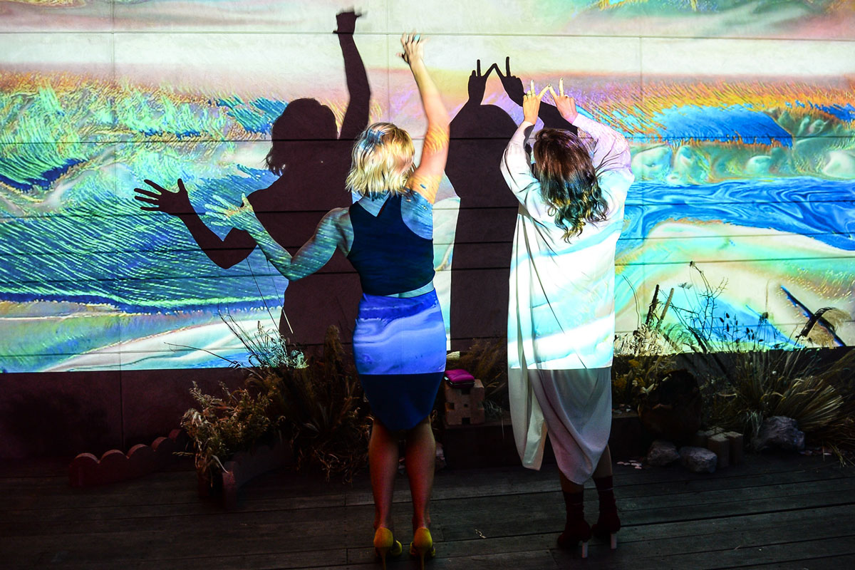 Two party guests dancing in front of a video projection