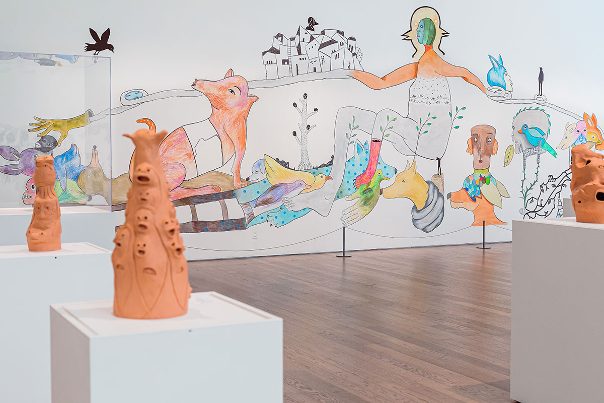 Ceramic sculptures on plinth with a large colourful mural in the background