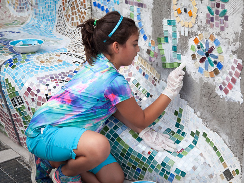 Child tiling a mosaic wall