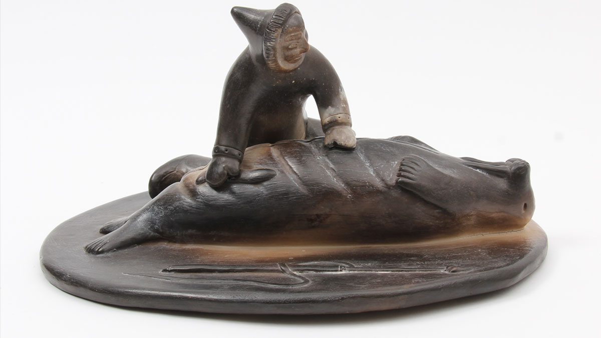 Ceramic sculpture of a man skinning a walrus