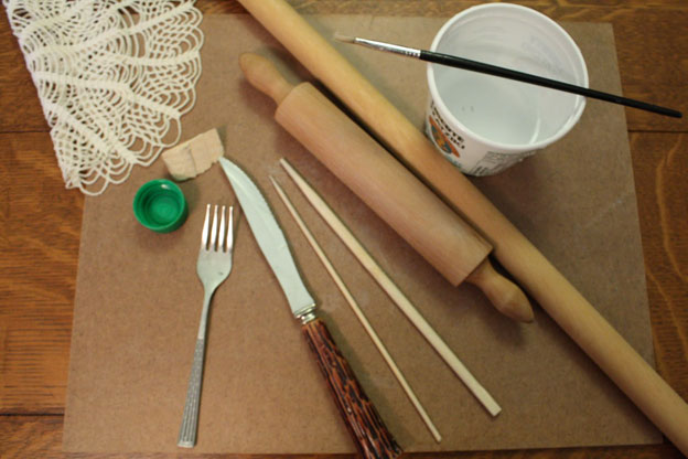 Assortment of art materials including a fork, rolling pin, and doily