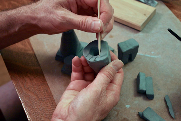 Using a skewer to scratch the surface of a clay object