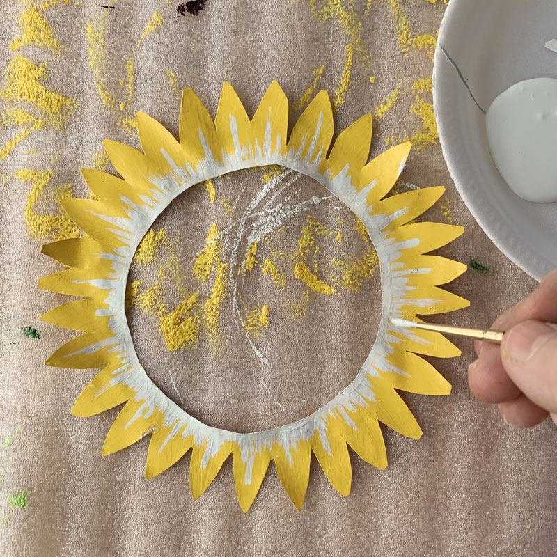 Paper sunflower being painted yellow with white details