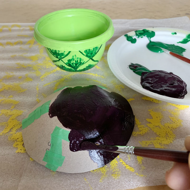 Painting a cardboard bowl with dark green paint