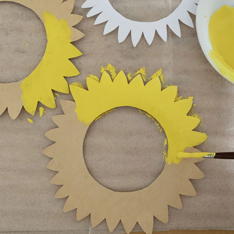 Cardboard sunflowers being painted yellow