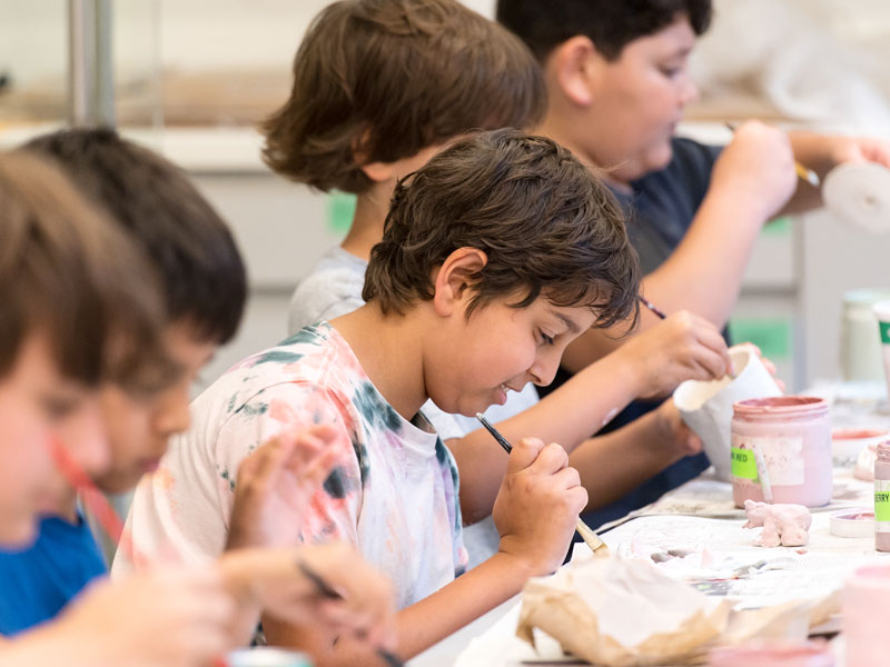 A group of campers at a table making pottery