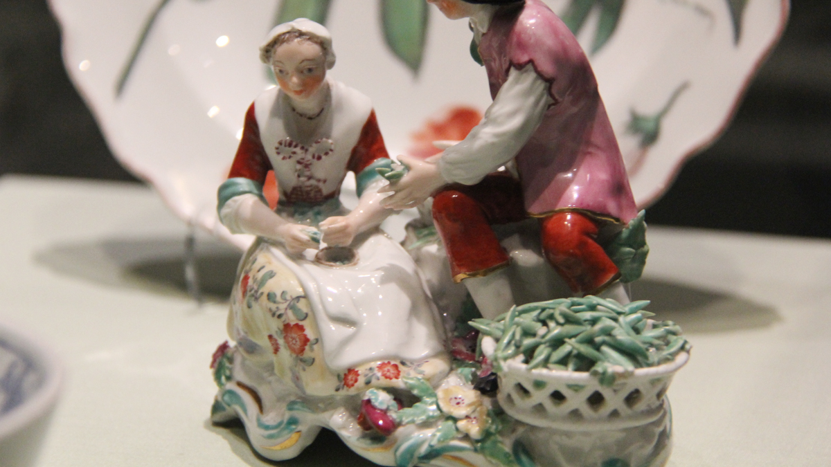 Two porcelain figures shelling peas