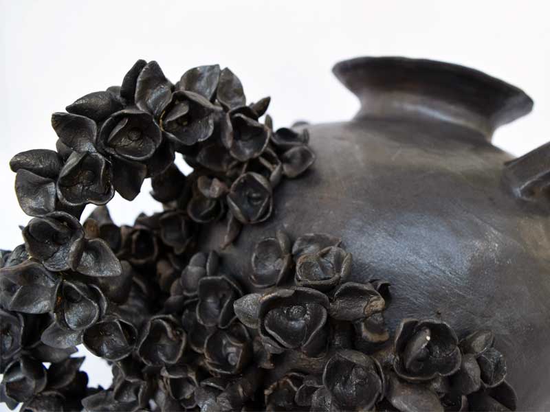 Close up of a black ceramic vessel with flowers