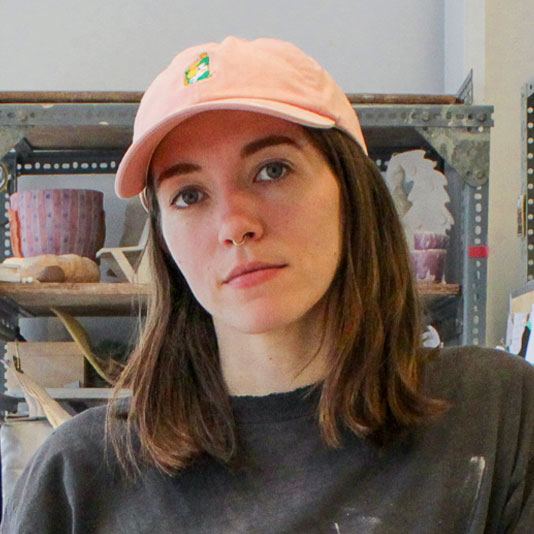 Artist Mel Wright wearing a pink baseball cap and black t-shirt in her studio
