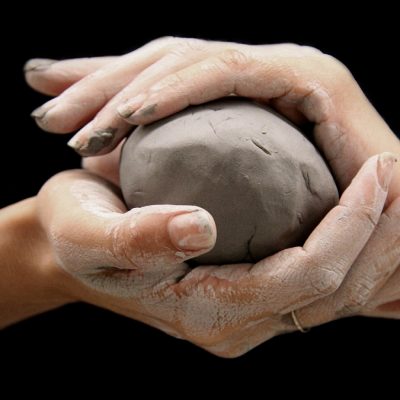 Hands wrapped around a ball of clay