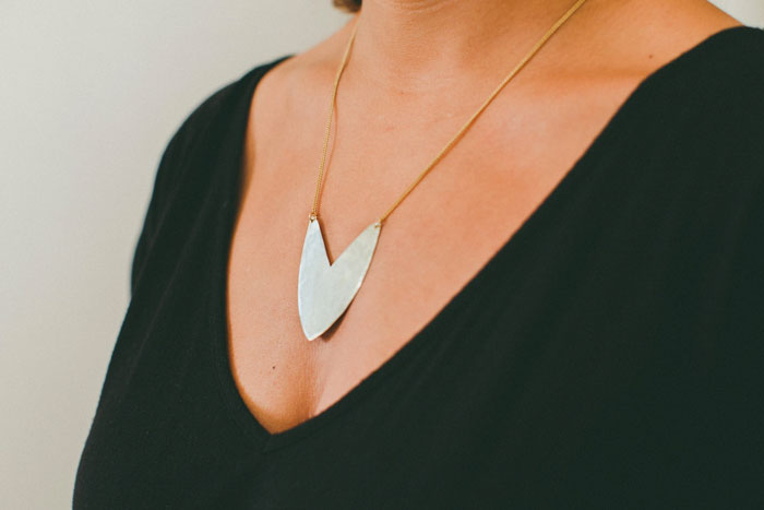 Woman wearing a silver necklace in the shape of a triangular shield