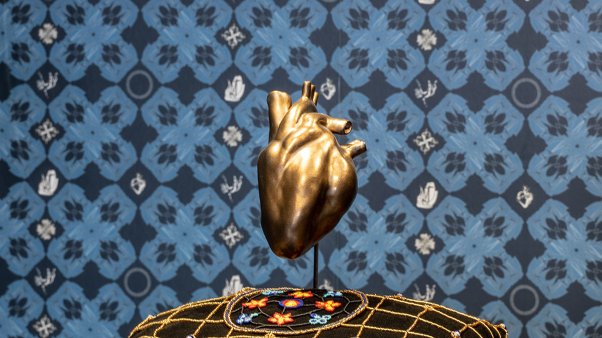 Gold ceramic heart sculpture on a pillow covered with beads