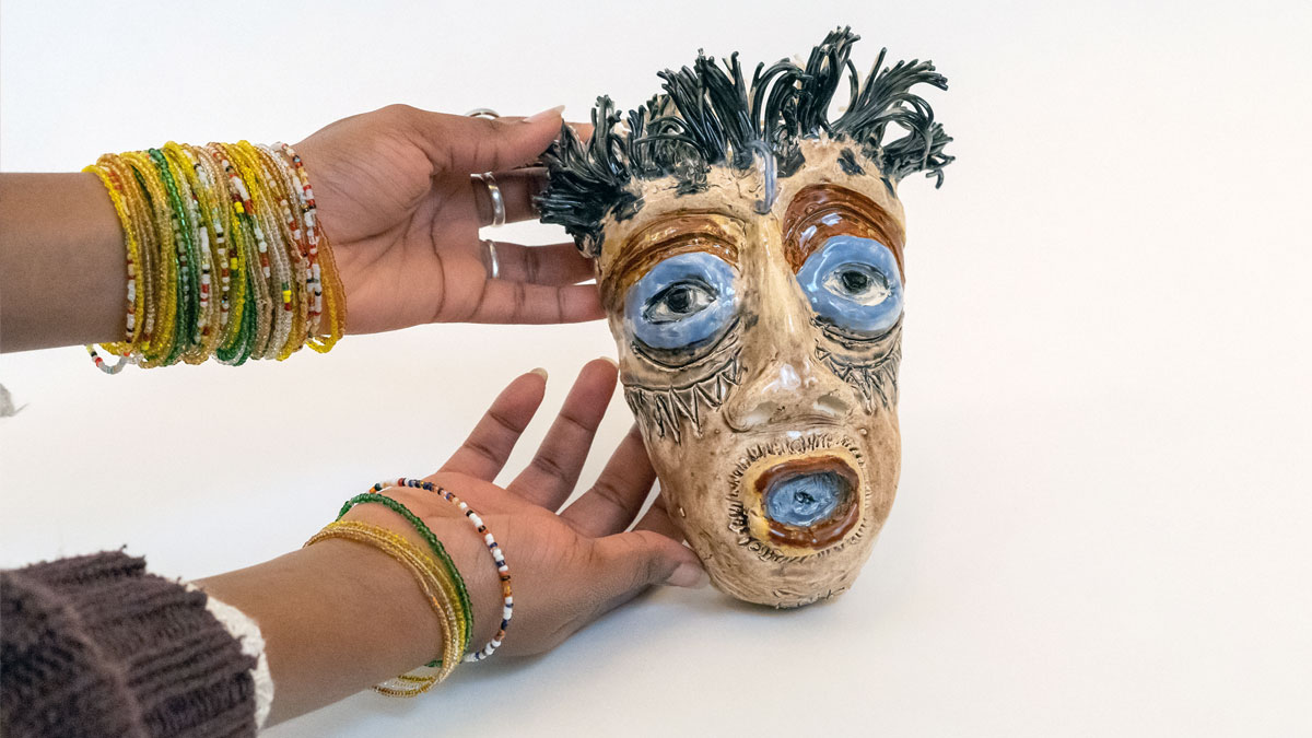 Hands holding a ceramic sculpture of a head