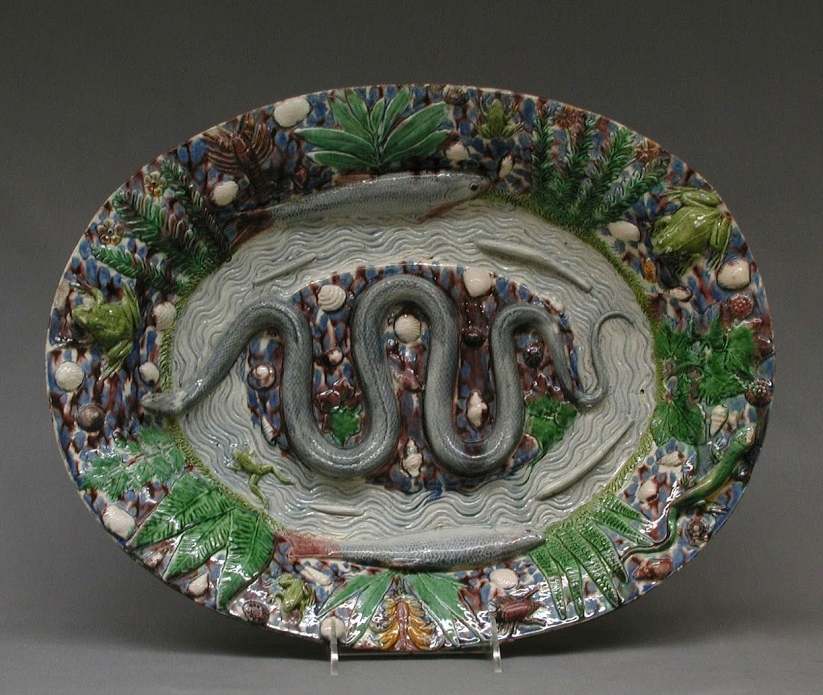 Ceramic plate with a snake in the centre and foliage around the border