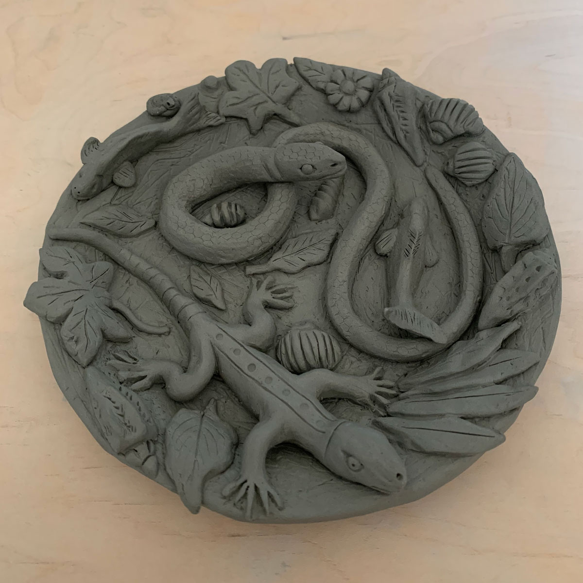 Clay plate with a snake, a lizard, leaves, and shells