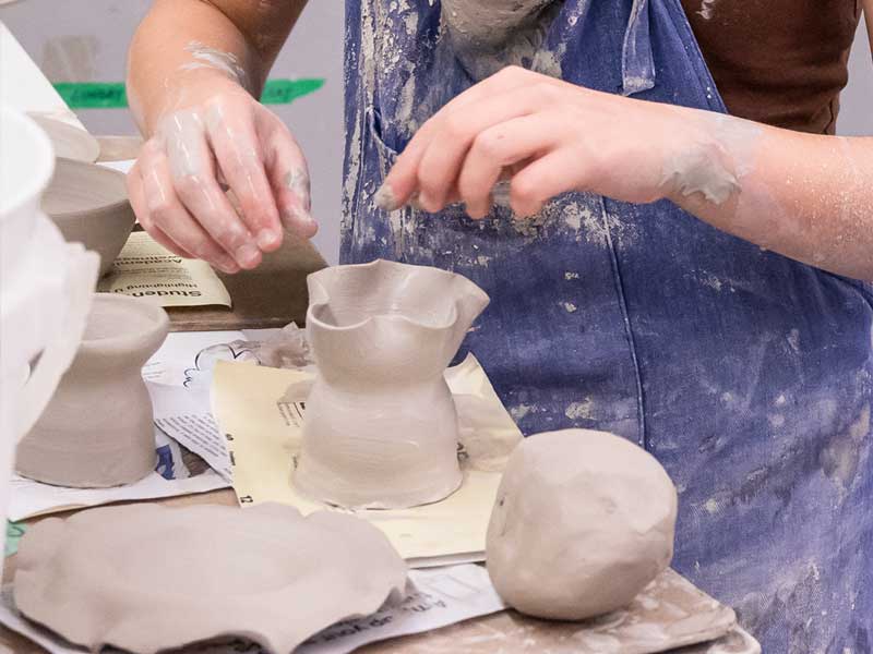 Hands of a young person working with clay