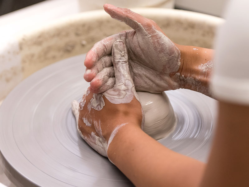 Hands of someone throwing on the pottery wheel