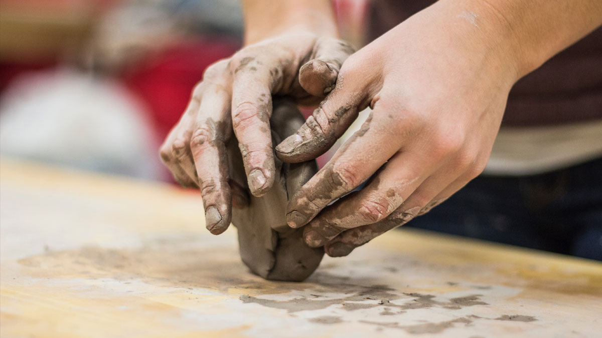 Hands moulding a chunk of clay